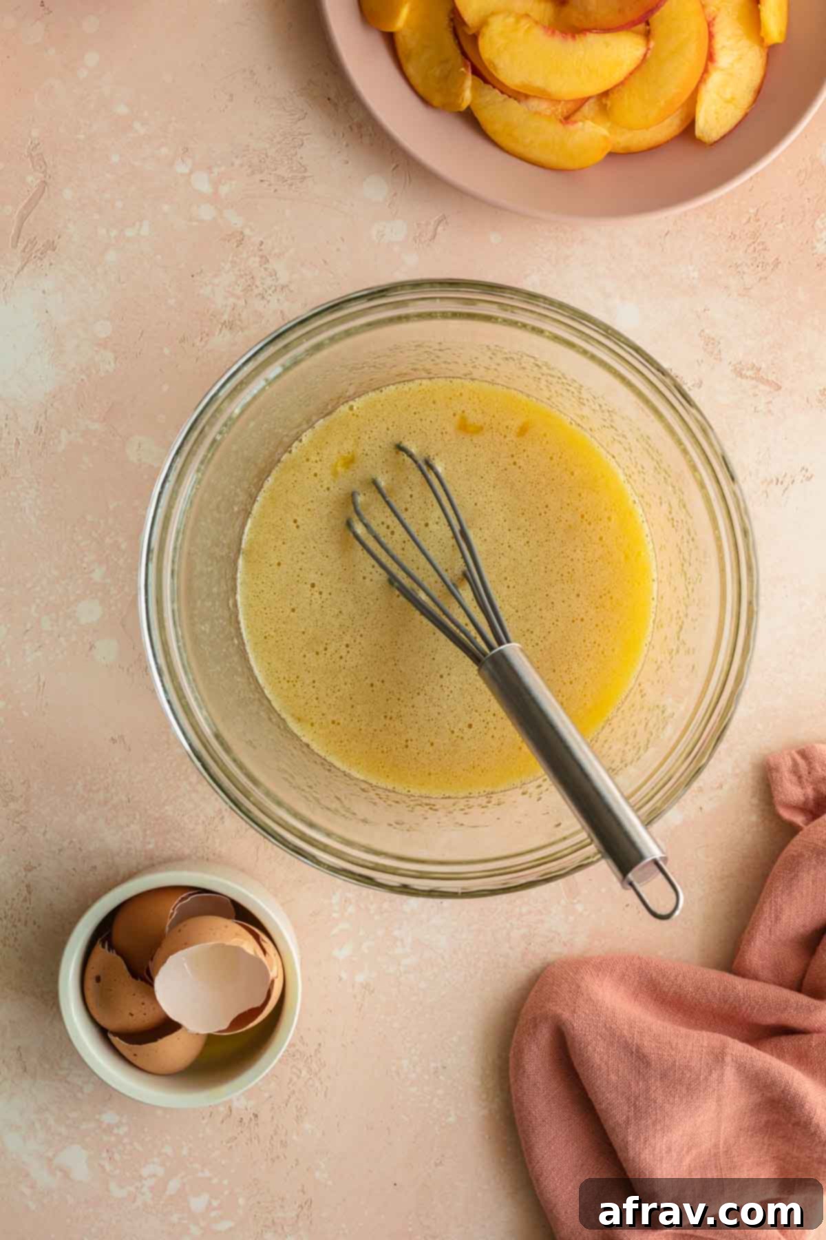 Wet ingredients being whisked together in a glass bowl.