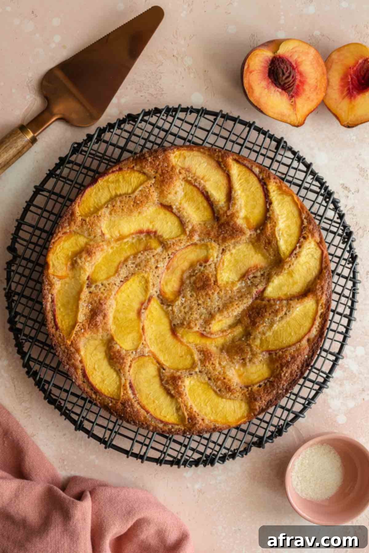 Overhead shot of a baked peach cake cooling on a round wire rack.