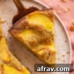 Slice of peach cake on a pink plate, showing the fluffy interior and peach topping.
