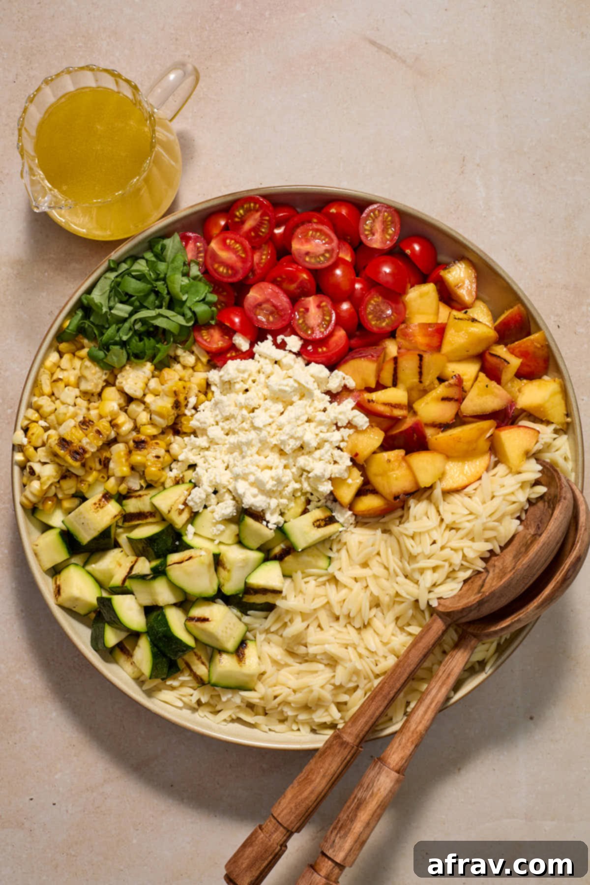 Charred Vegetable and Peach Orzo Summer Salad 9 All of the salad ingredients sectioned in a large bowl with dressing on the side.