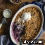 Healthy blueberry crisp baked up in a blue dish and topped with ice cream.