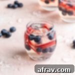 White Wine Spritzer with Fruit in a wine glass on a pink surface.