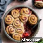 Strawberry Basil Cobbler with Wholesome Swirl Biscuits 2 Overhead view of strawberry basil cobbler in a pie dish on a pink surface.