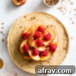 Overhead view of dairy-free frozen peach cream pie topped with fresh peaches, raspberries and granola.