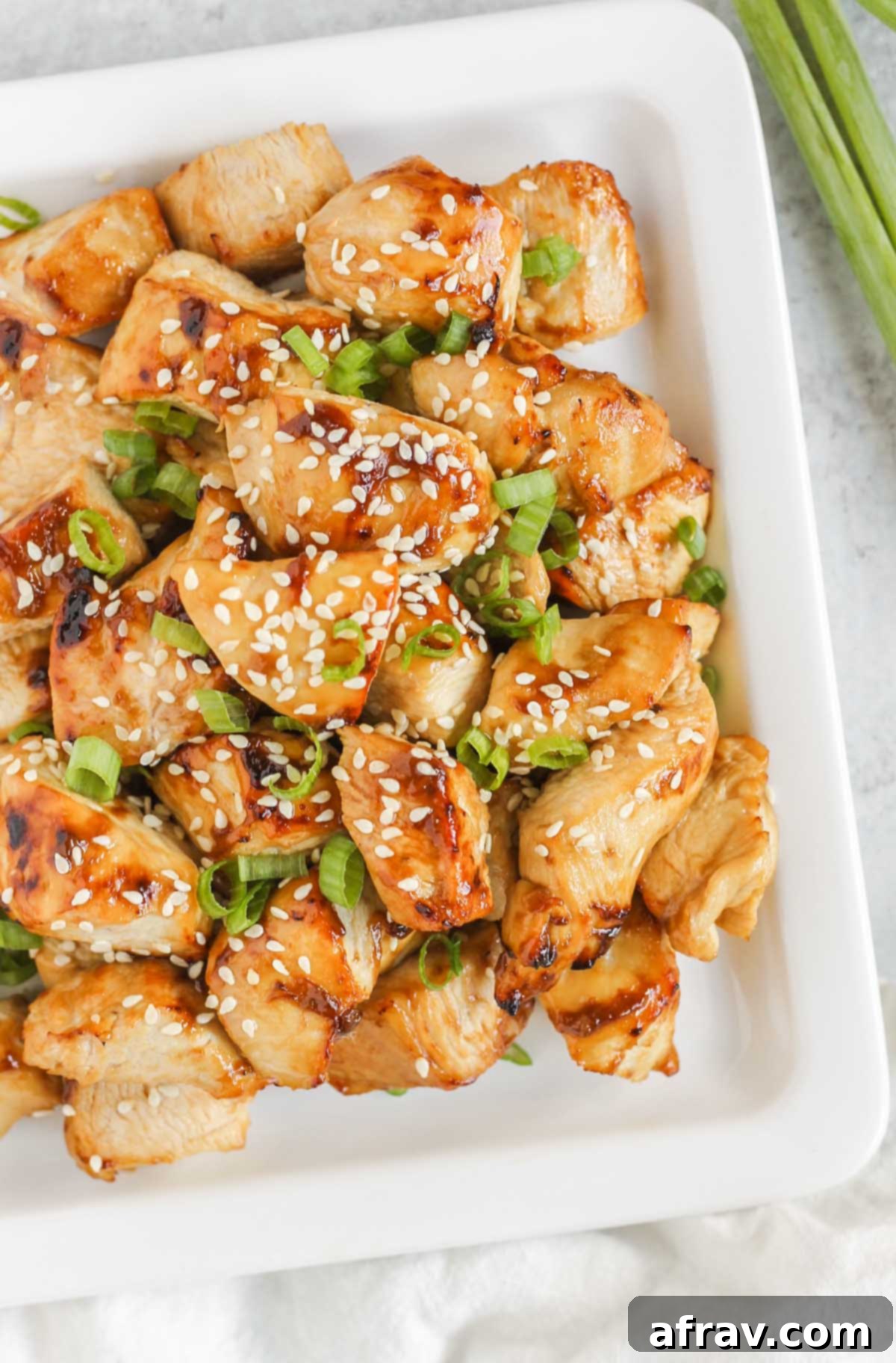 Chicken pieces sprinkled with sesame seeds and green onions.