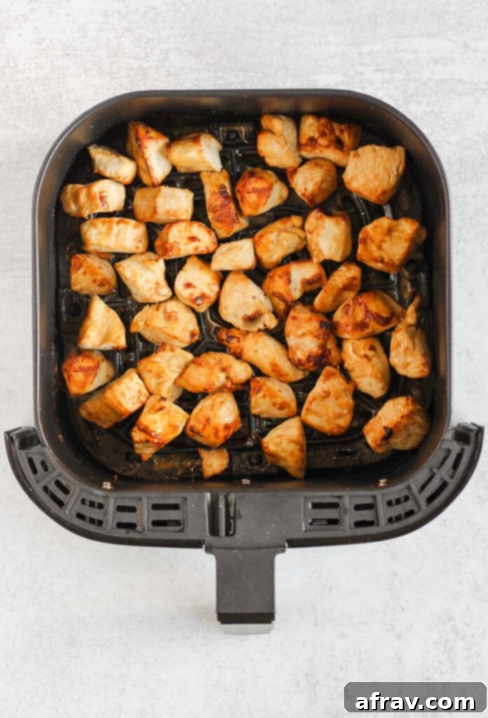 Cooked teriyaki chicken pieces in air fryer basket.