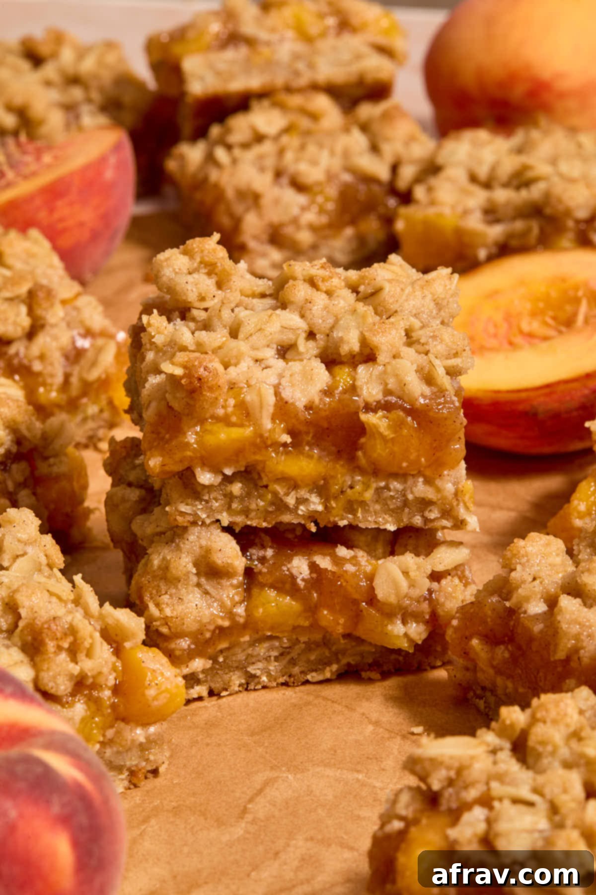 Peach bars arranged on top of each other with halved peaches in view, showcasing their delicious layers.