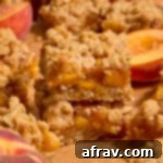 Two almond flour peach crisp bars stacked on top of each other on brown parchment paper.