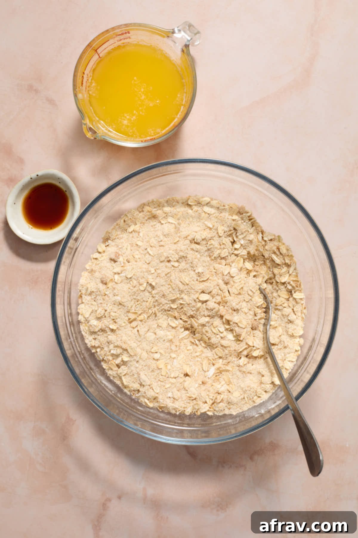 Dry ingredients stirred together in a glass bowl with melted butter and vanilla on the side.