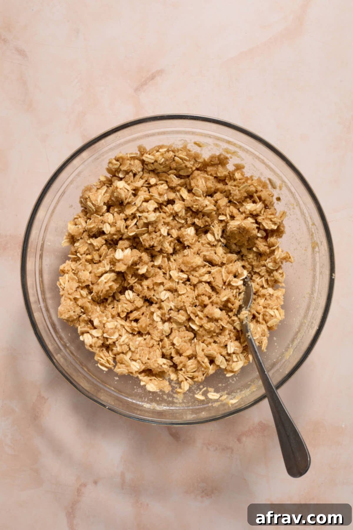 Oat mixture mixed together in a glass bowl with a fork, showing crumbly texture.
