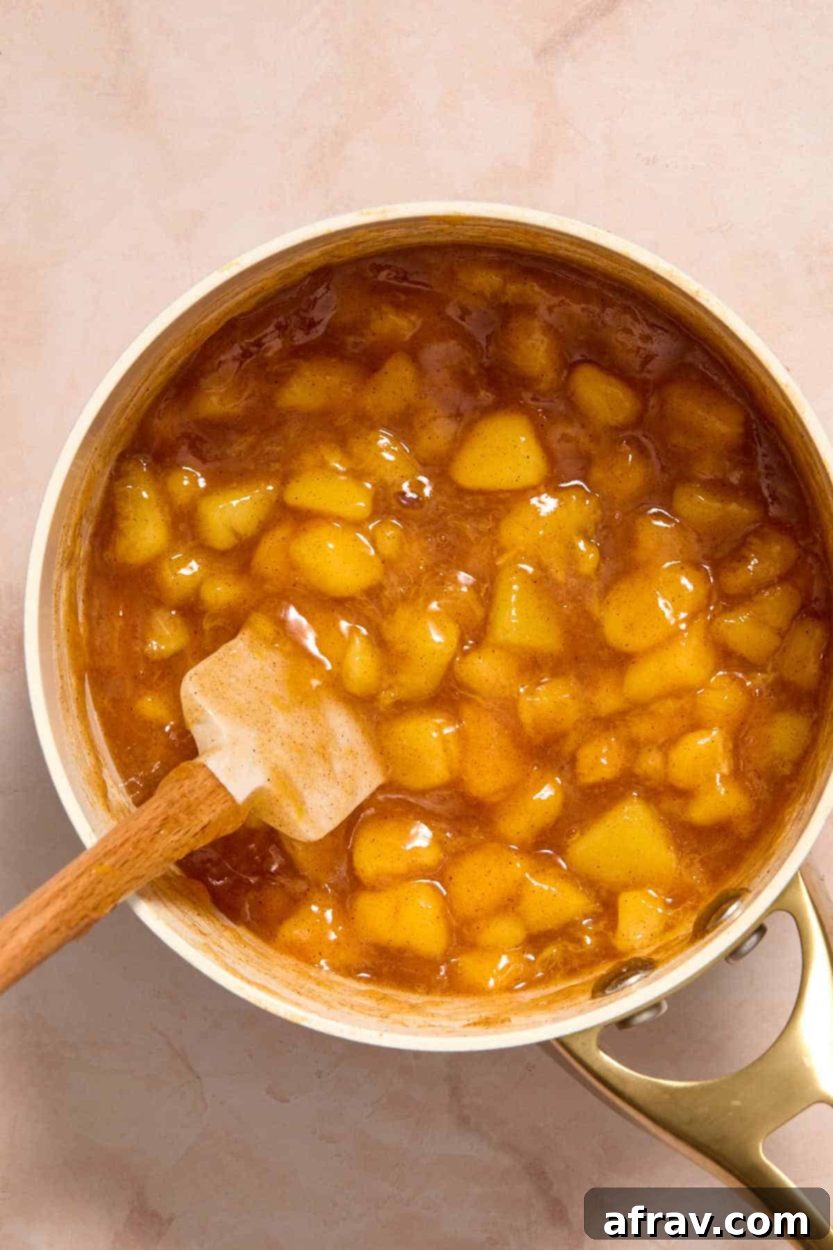 Cooked peach filling in the saucepan with a spatula, showing its thickened consistency.