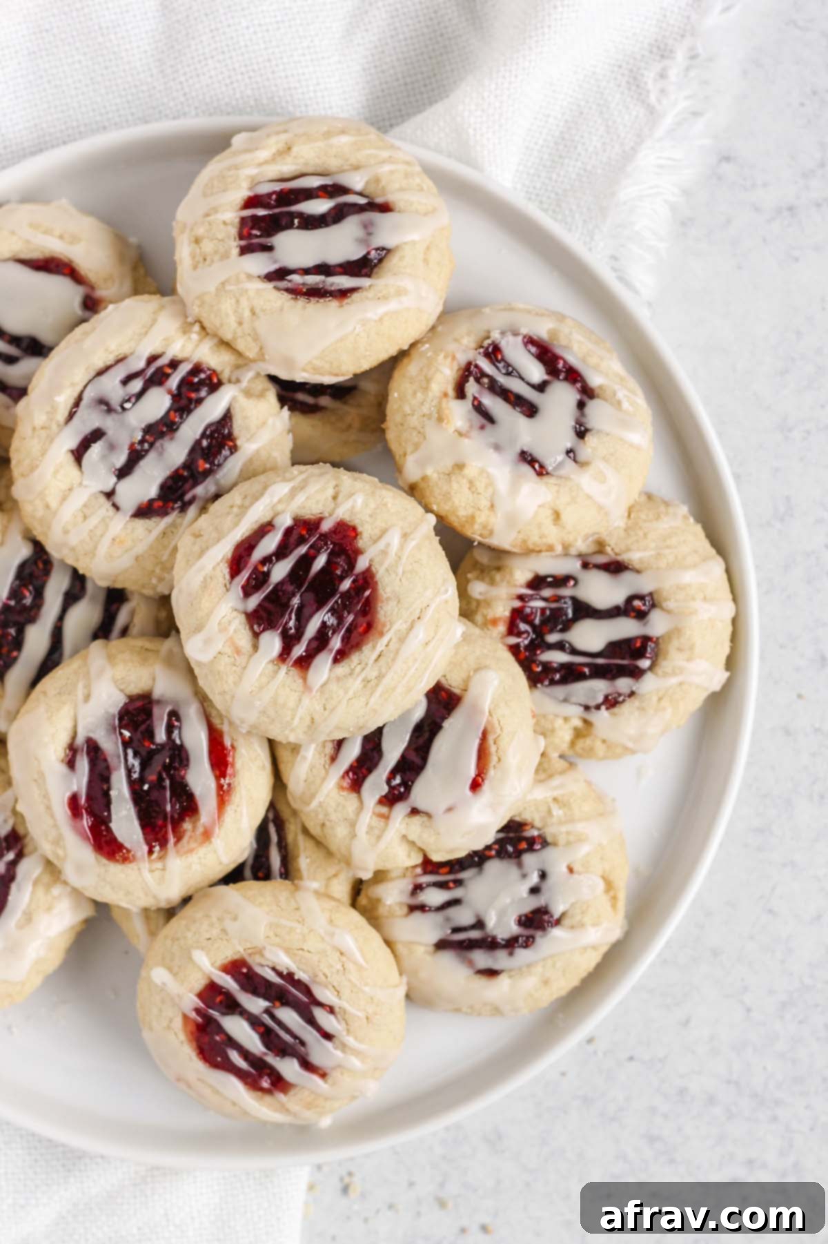 Overhead view of gluten-free raspberry thumbprint cookies arranged artfully on a white plate, ready to be served.
