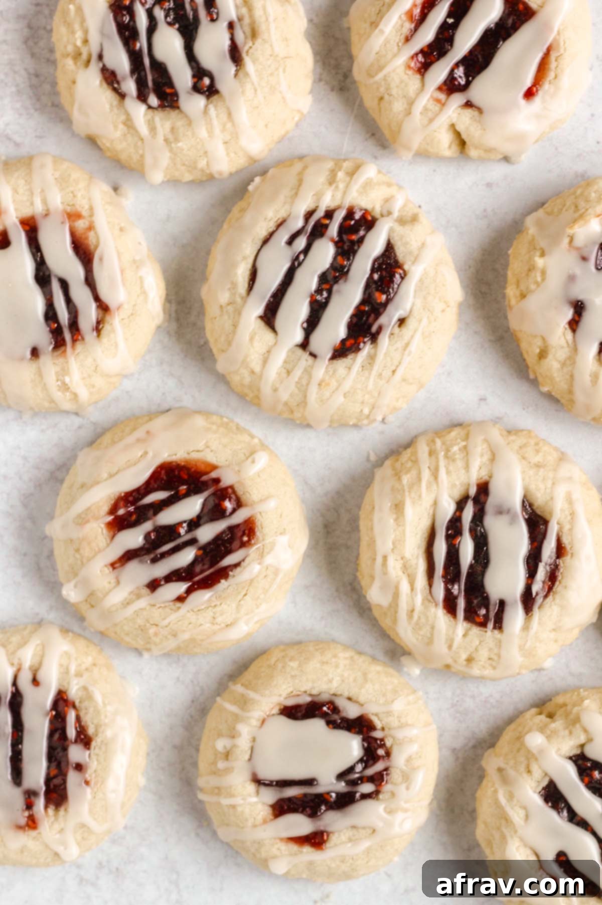 Close up of gluten-free thumbprint cookies drizzled with glaze, highlighting the delicate almond icing.
