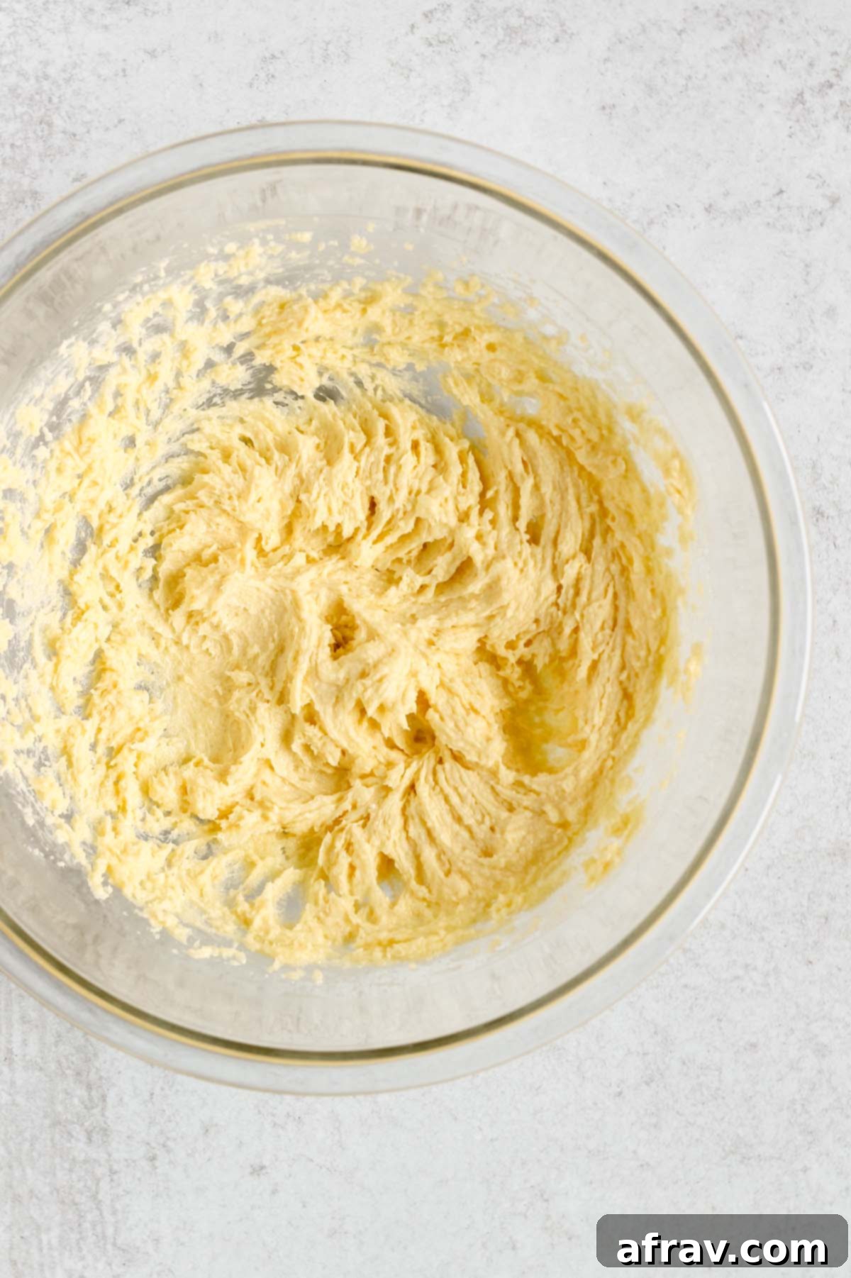 Butter and sugar creamed together in a glass mixing bowl, looking light and fluffy.