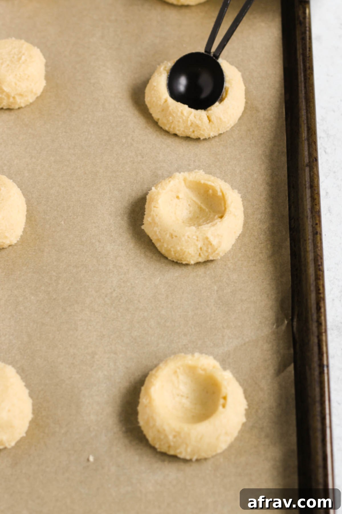 Dough balls with perfect indents made by a teaspoon, ready for jam.