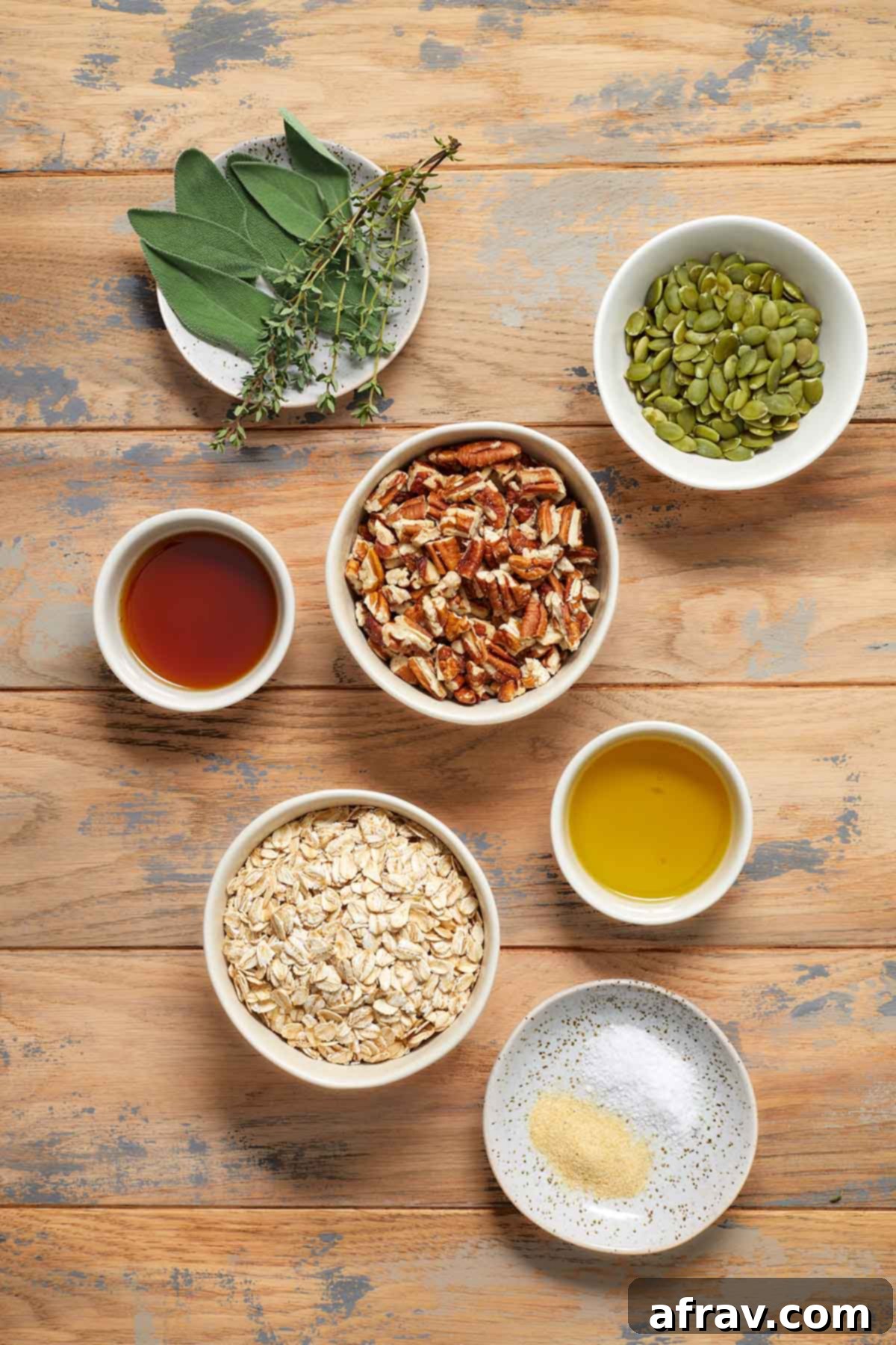 Robust Pecan Crunch Granola 3 Ingredients to make savory granola arranged individually on a wooden table, including oats, pecans, pumpkin seeds, and fresh herbs.