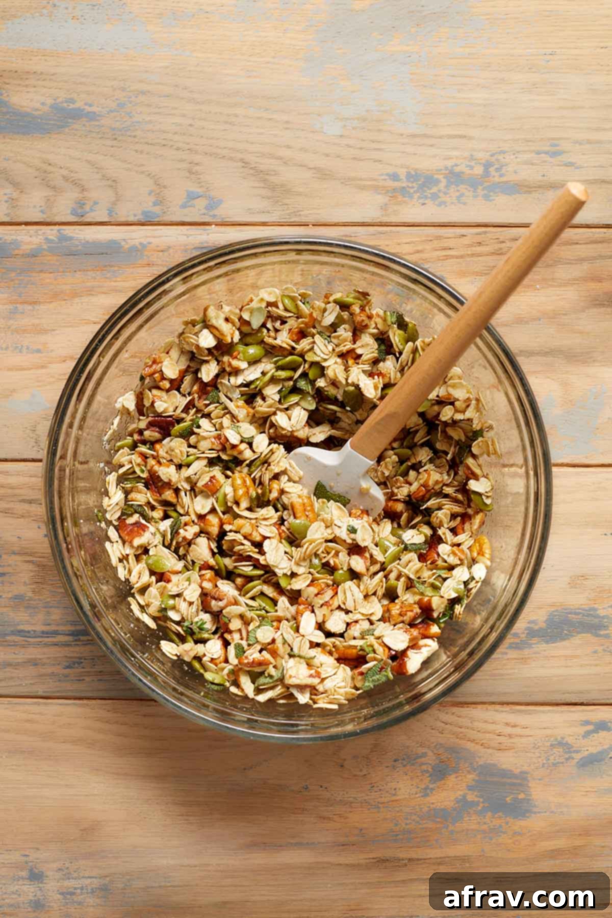 Robust Pecan Crunch Granola 4 Granola ingredients mixed together in a glass bowl with a spatula, showing the even coating.