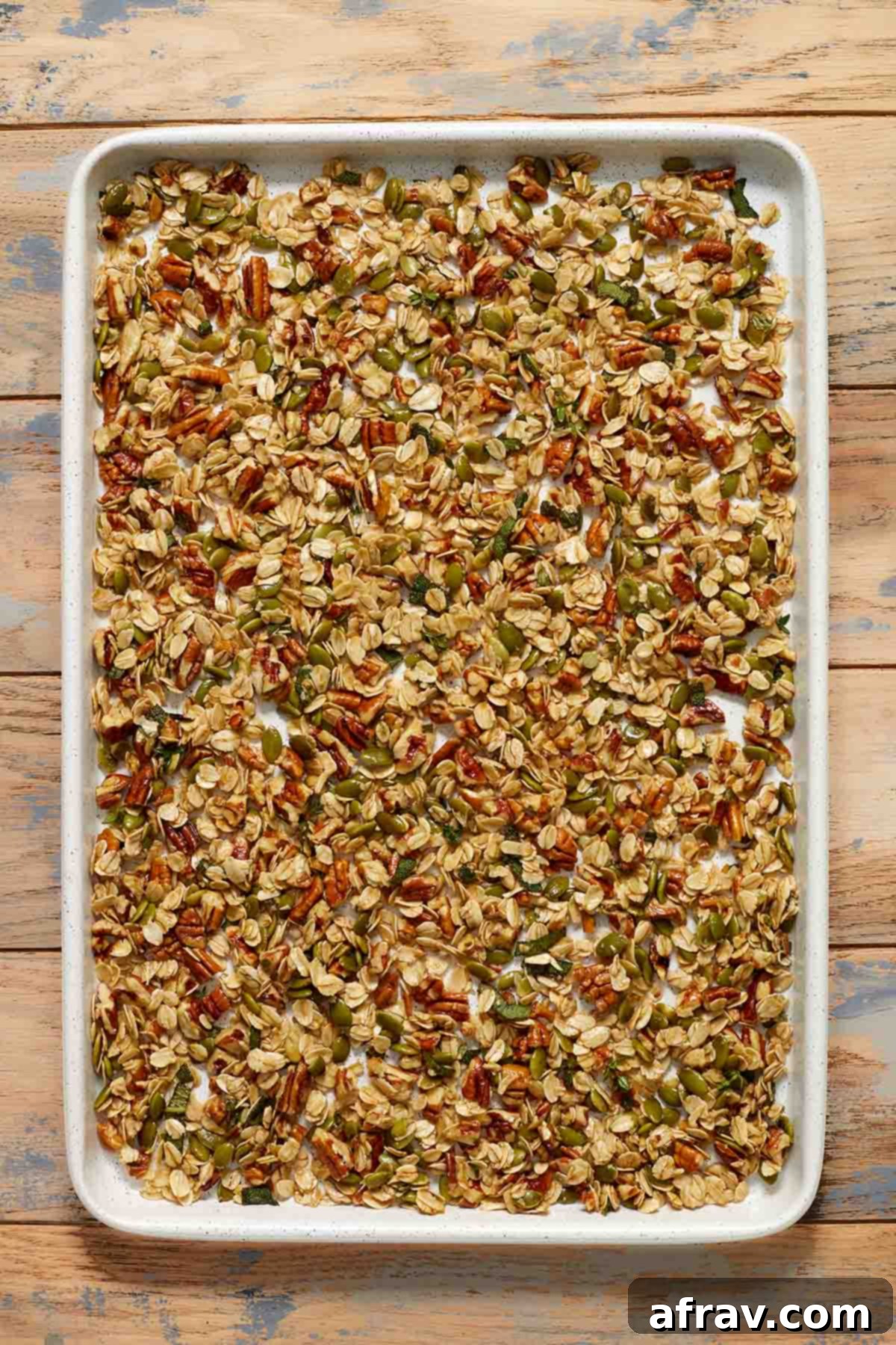 Robust Pecan Crunch Granola 5 Granola mixture spread out on a large baking sheet, ready for baking.
