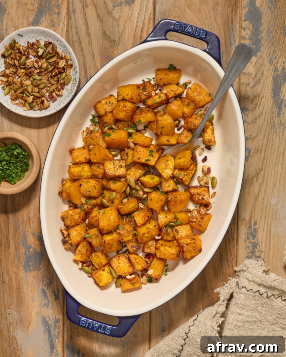 Perfectly roasted butternut squash cubes served in a rustic dish with a spoon, ready to be enjoyed.