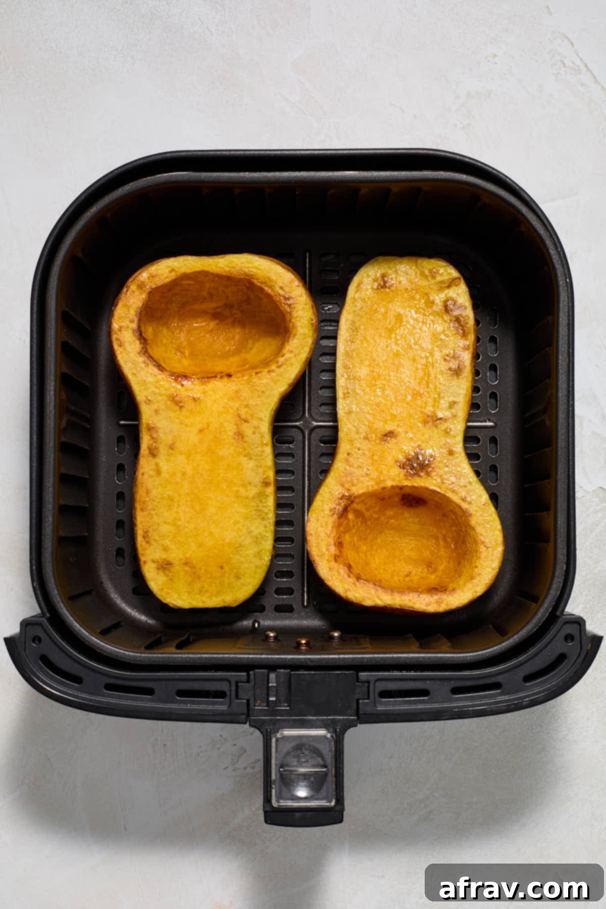 Butternut squash halves, partially air-fried for 15 minutes, showing a slightly softened texture.