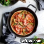 Overhead view of Healthy Homemade Pizza baked up in a cast iron skillet next to a bowl of salad.