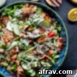 Overhead view of spicy salmon pasta salad in a blue bowl on a dark surface.