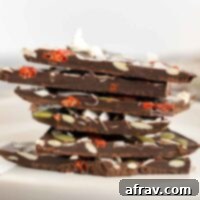 Pieces of healthy dark chocolate bark stacked on top of one another, showing the rich chocolate and colorful toppings.