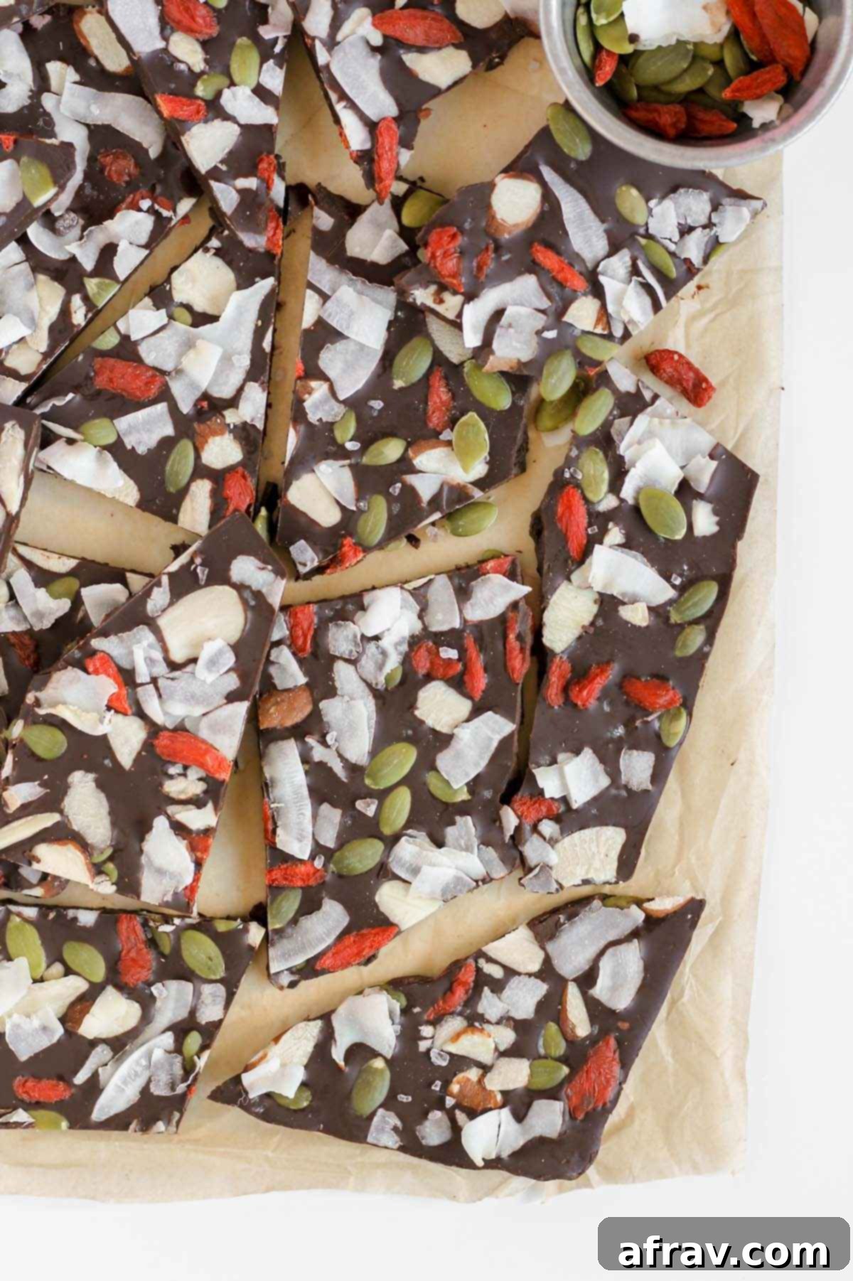 Numerous pieces of healthy dark chocolate bark arranged artfully, highlighting the vibrant colors and appealing textures of the toppings.