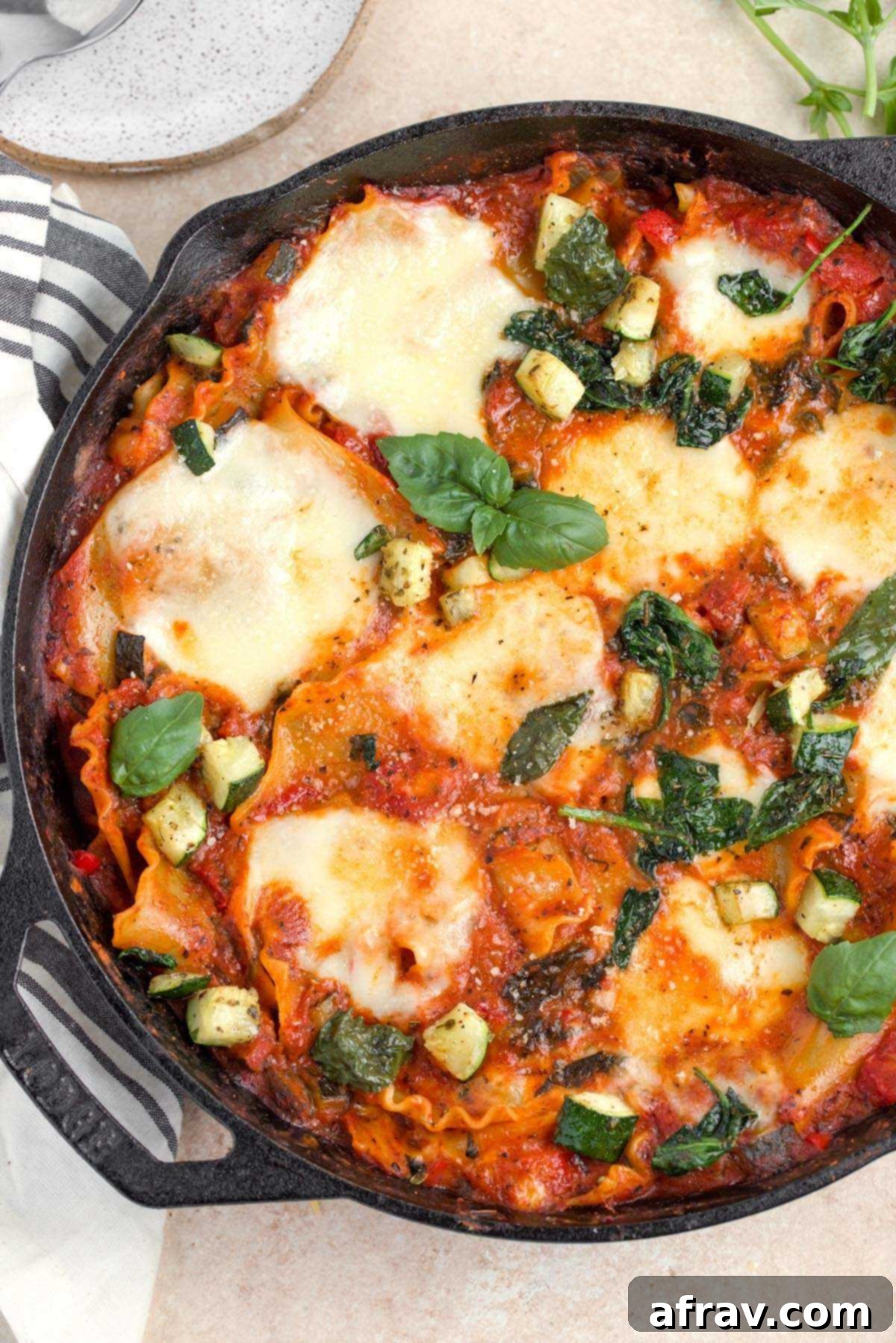 Overhead view of vegetarian lasagna skillet in a cast iron pan, garnished with fresh basil.