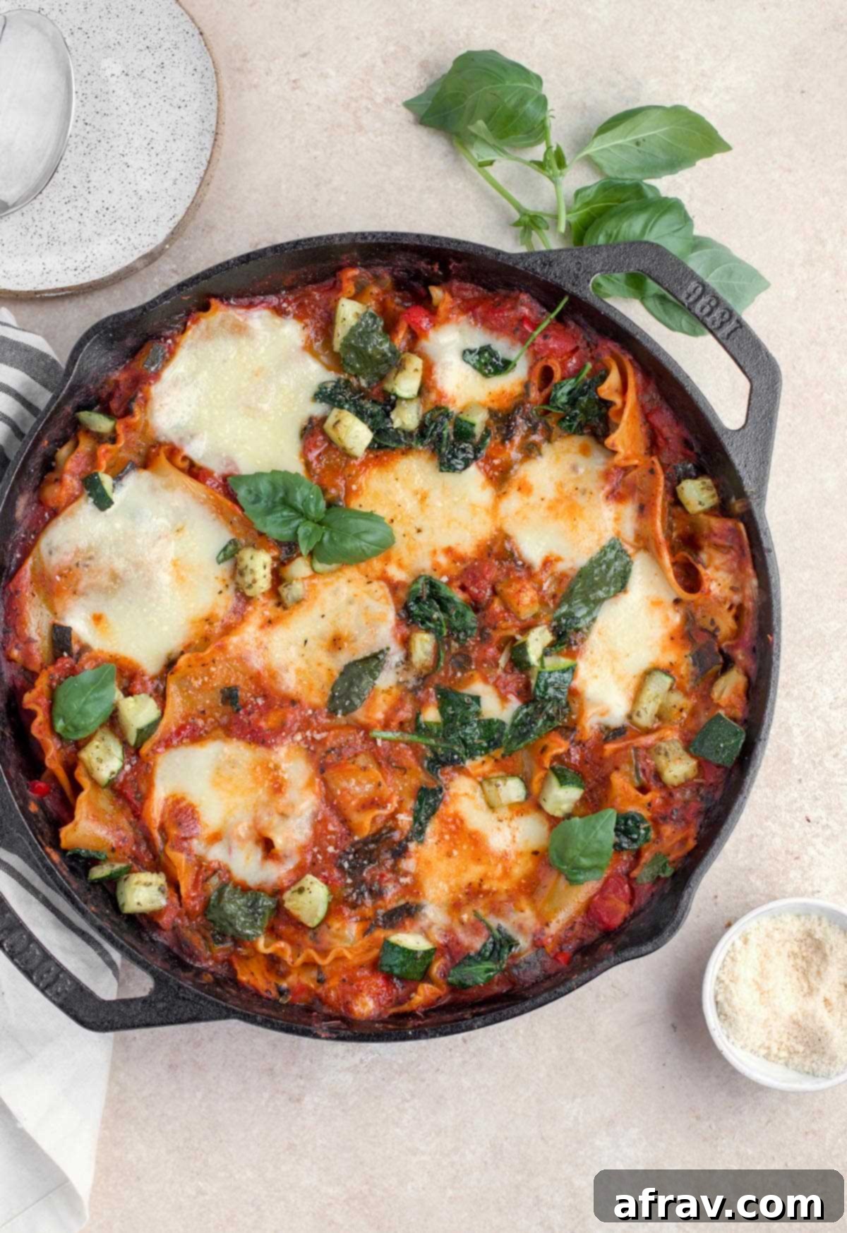 An overhead view of this homemade vegetarian lasagna in cast iron skillet, garnished with fresh basil.