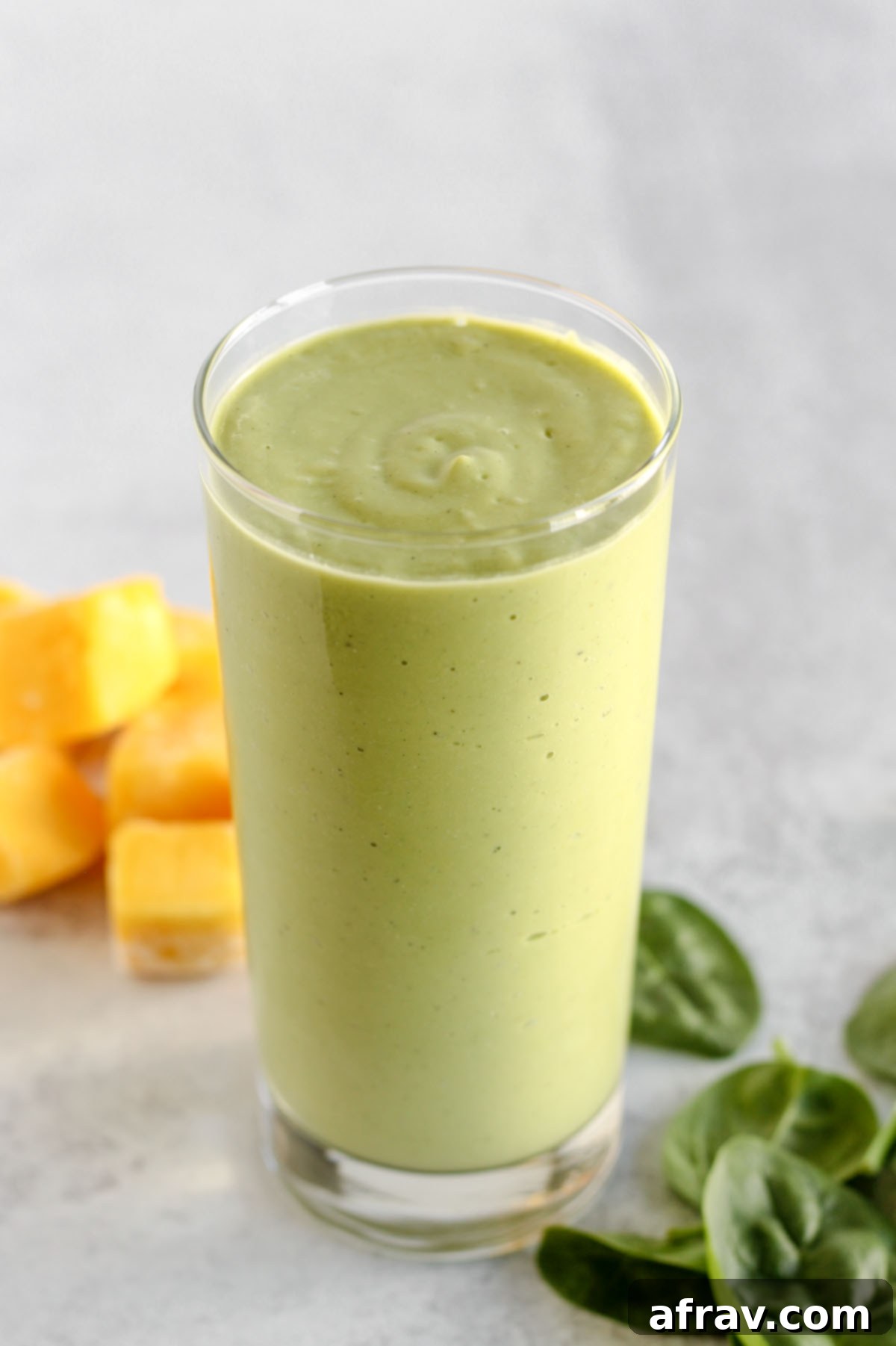 Creamy green smoothie in a tall glass, beautifully presented, inviting a refreshing sip.