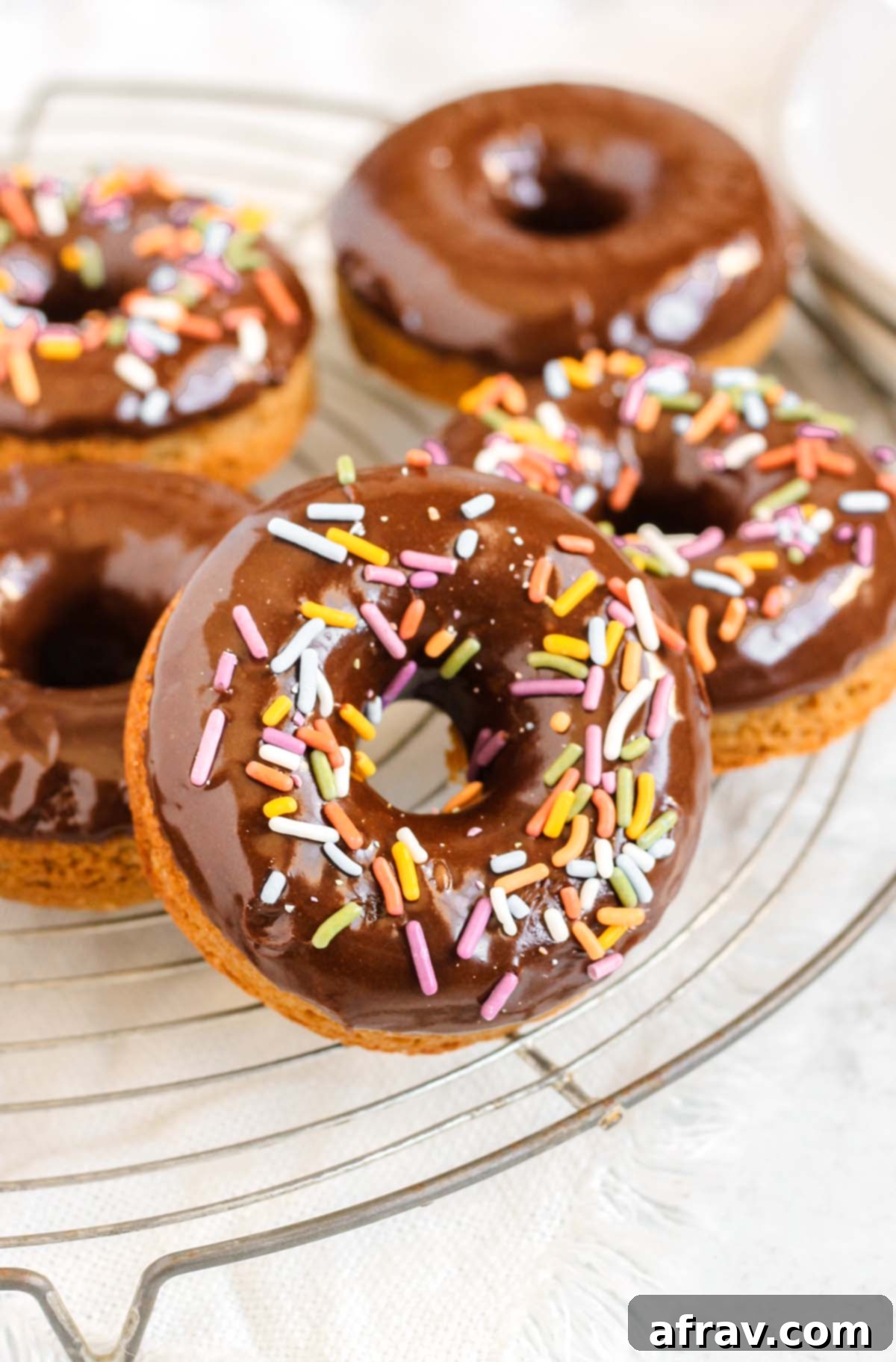 Close up of sprinkled chocolate donut on a cooling rack.