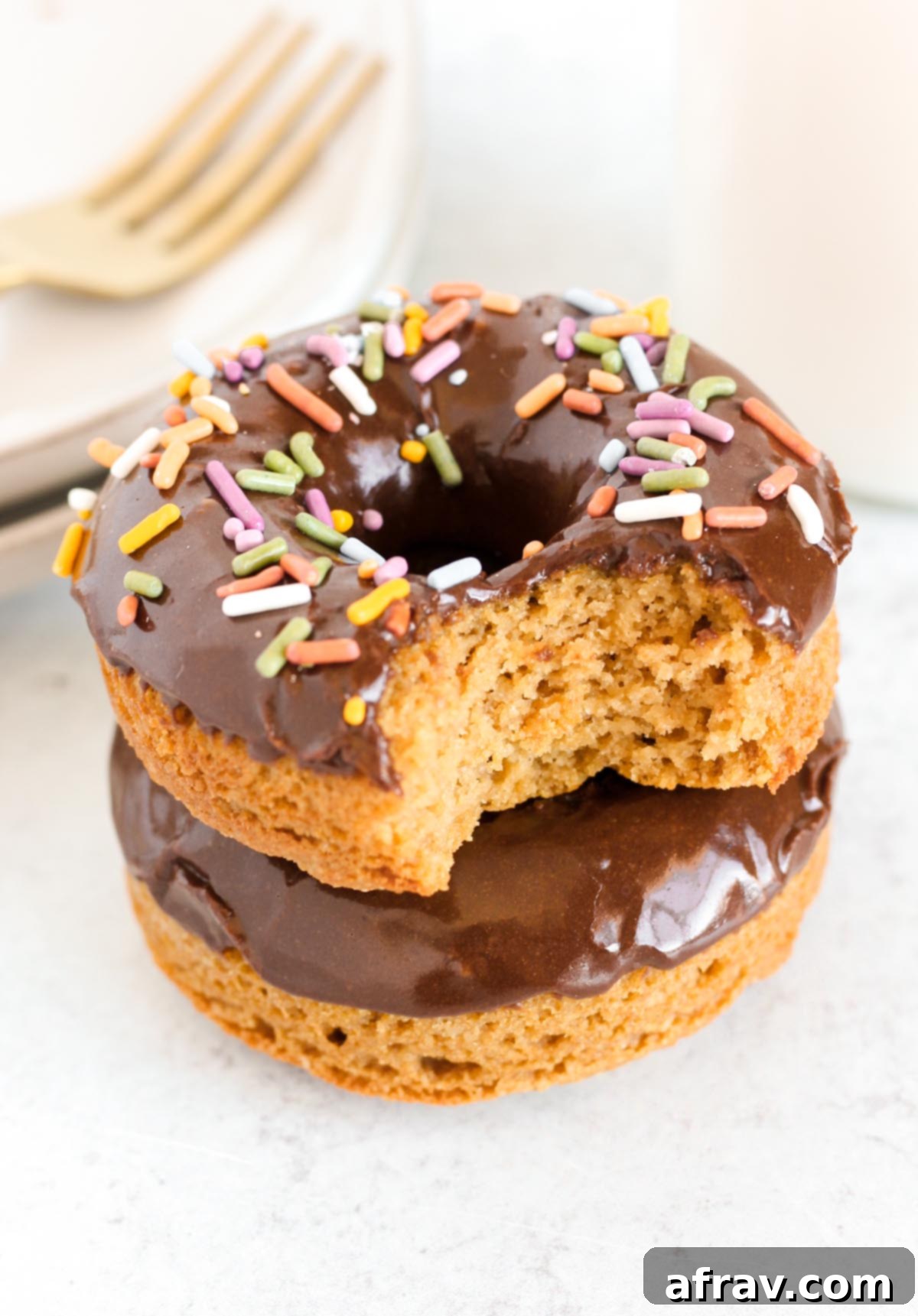 Chocolate covered donut with sprinkles with a bit taken out of it.