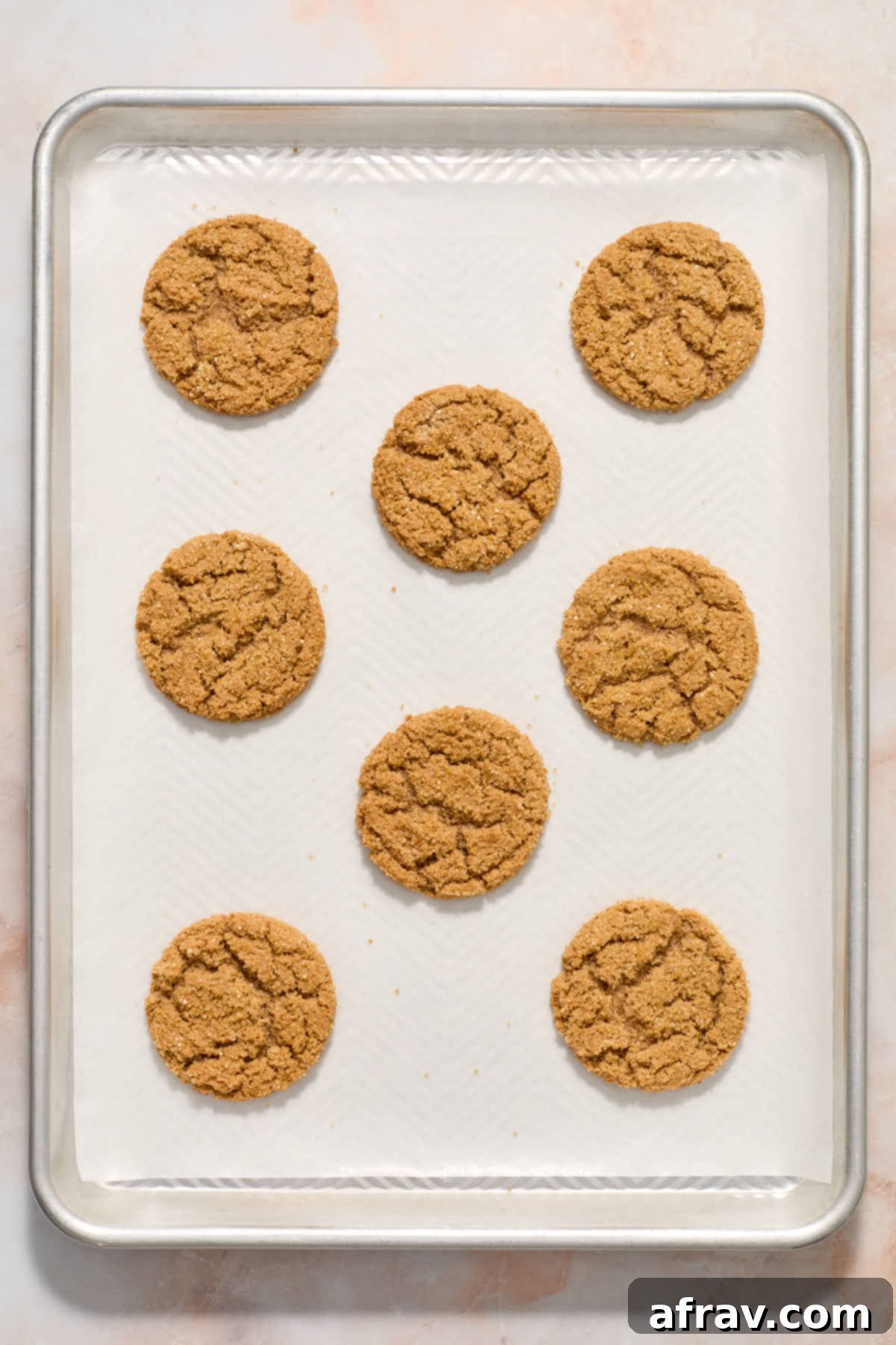 Freshly baked cookies cooling on a baking sheet, showing their golden edges and soft centers.