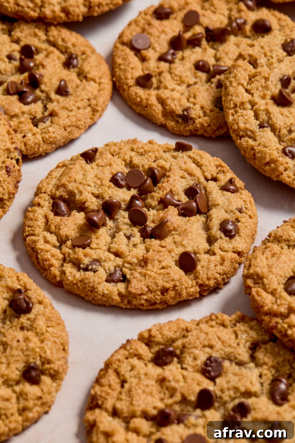A stack of three almond flour cookie butter cookies with mini chocolate chips, on a rustic surface.