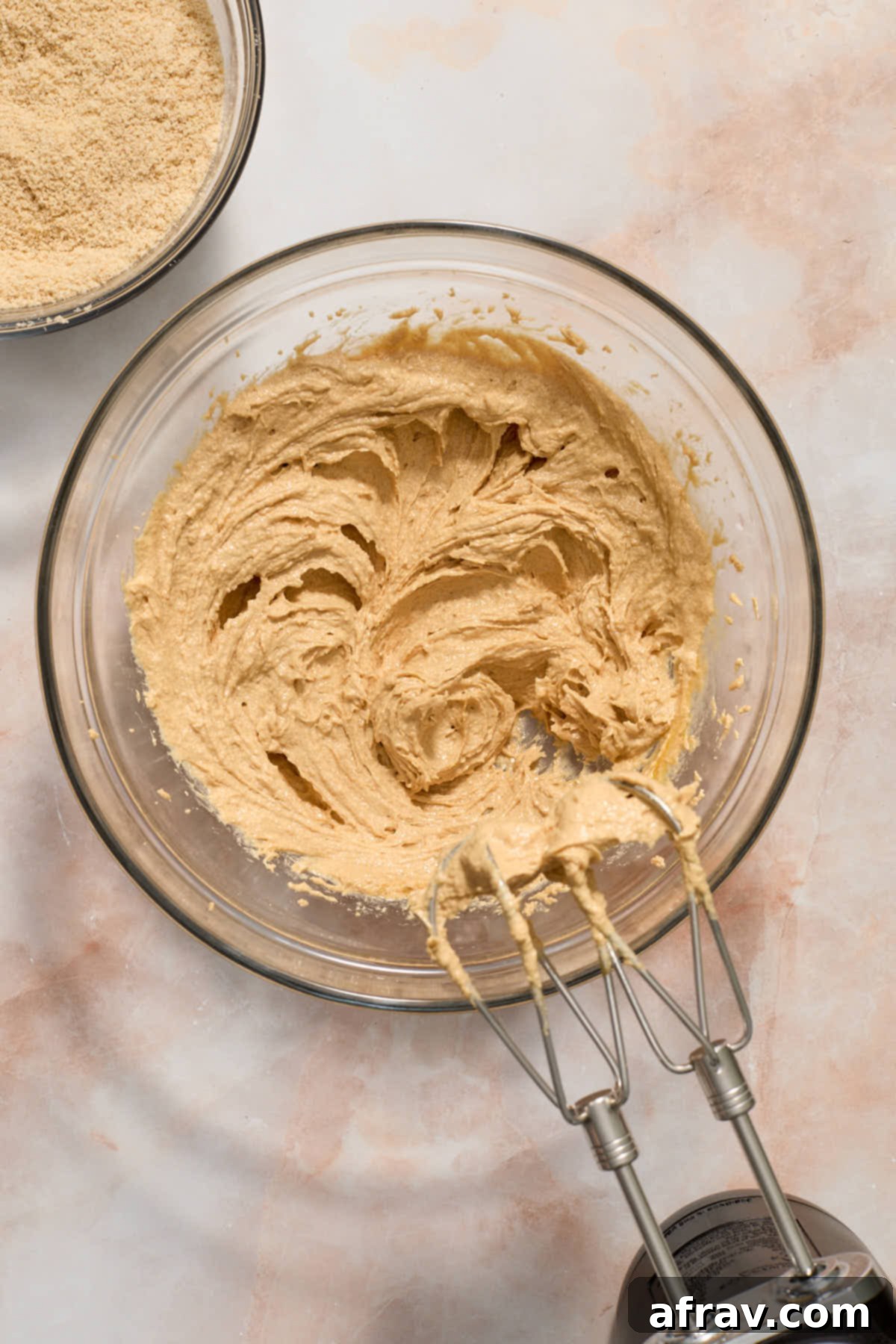 A large egg and vanilla extract being beaten into the creamed wet mixture.