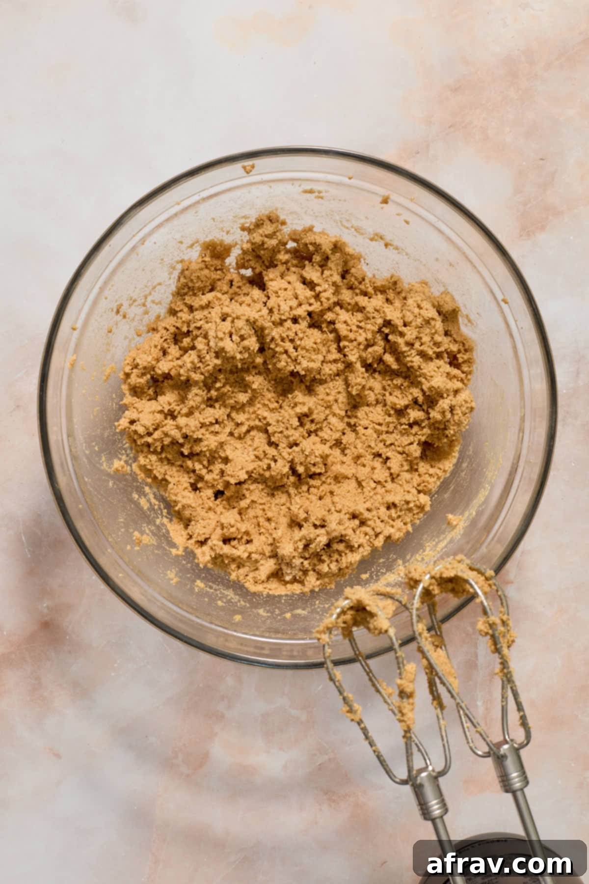 The dry ingredients being gradually mixed into the wet mixture using a hand mixer, forming cookie dough.