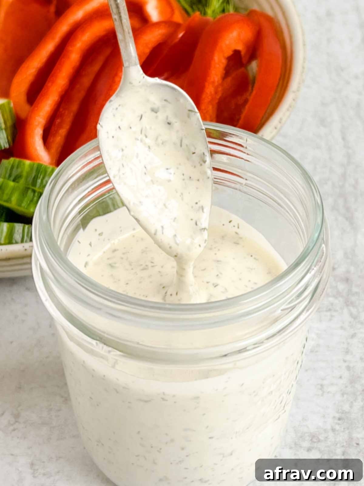 Effortless Dairy-Free Paleo Ranch Dressing 6 Spoon dripping with homemade dairy-free ranch dressing over a mason jar.