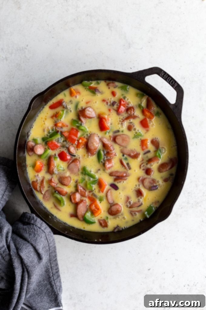 Sausage frittata topped with egg mixture and ready for the oven.