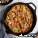 Sausage frittata with peppers and onions in a black cast iron skillet.