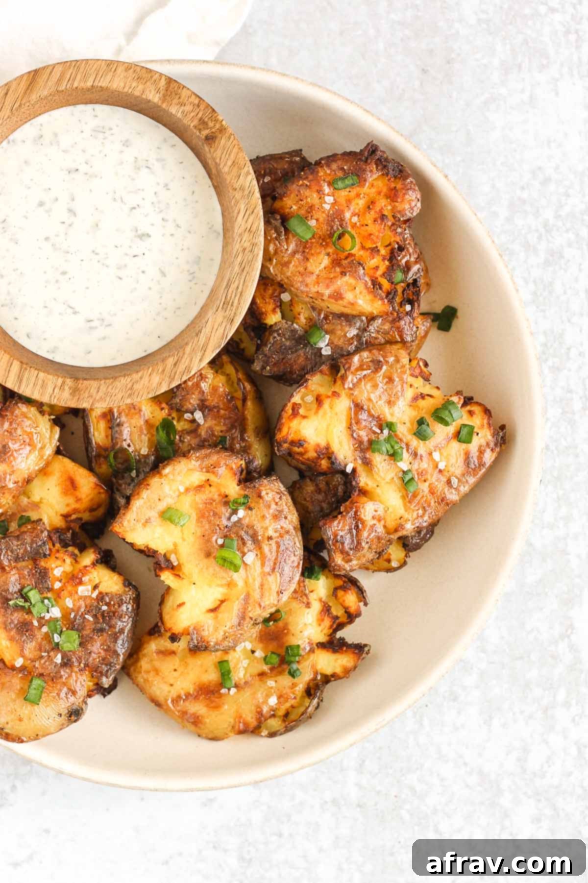 Fried smashed potatoes on a plate with a side of ranch.