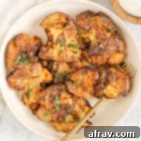 Fried smashed potatoes on a round serving plate with a gold fork.