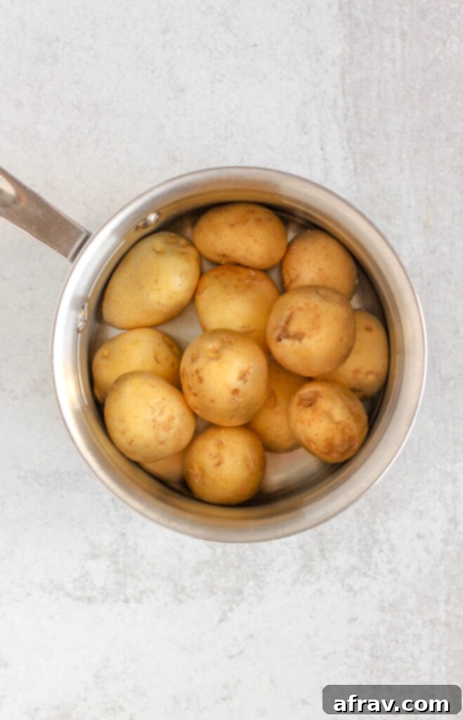 Stainless steel pot filled with water and potatoes.