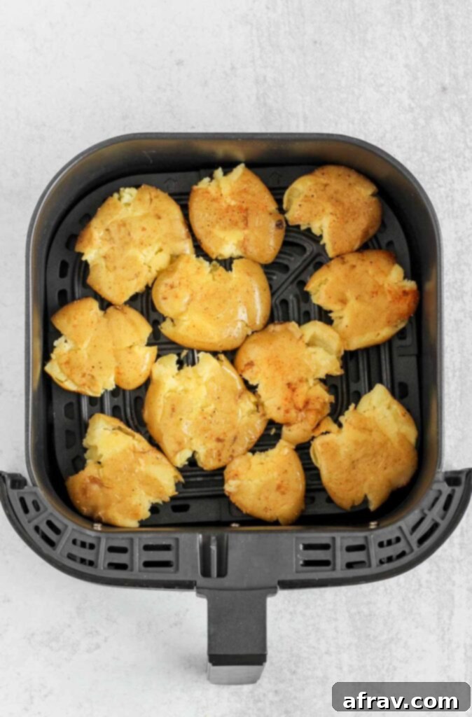 Air fryer basked with pre-fried smashed potatoes.