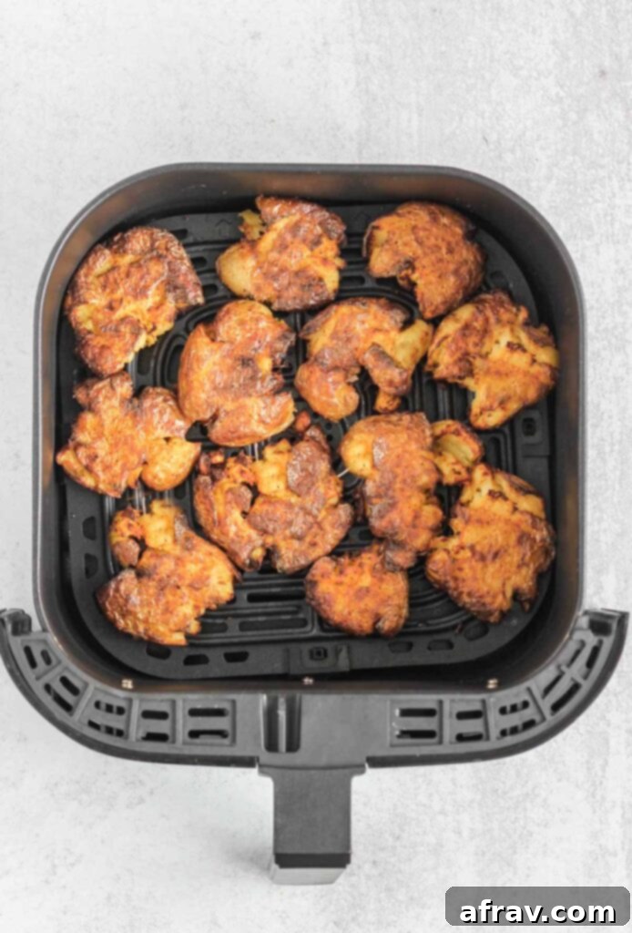 Fried smashed potatoes in an air fryer basket.