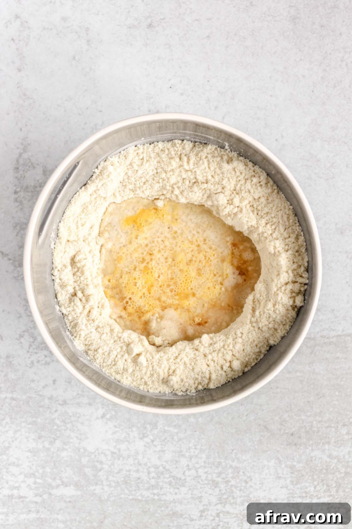 Flour mix in a mixing bowl with a well in the center filled with wet ingredients.
