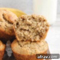 Banana muffins stacked 2 high with top one cut open to show texture.