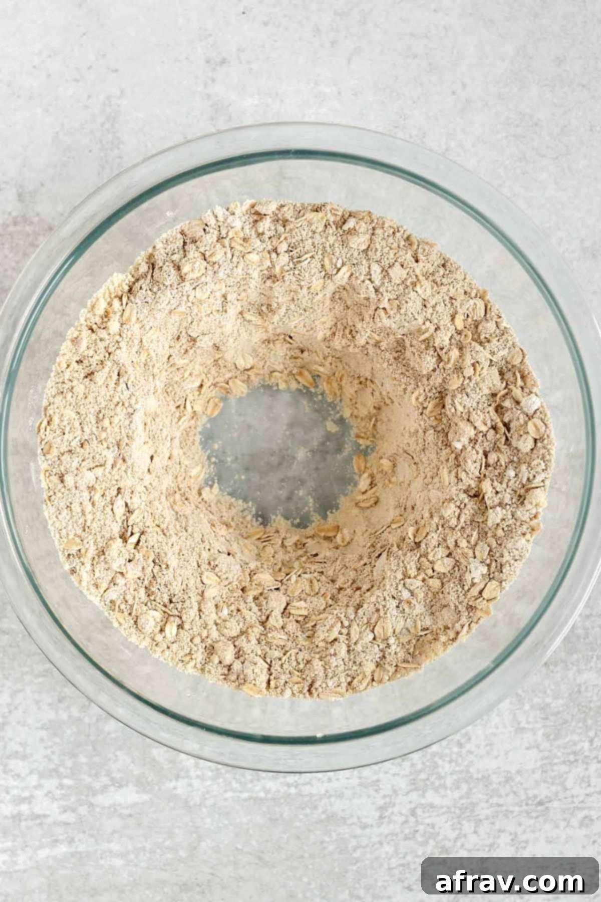 Dry ingredients for gluten-free banana muffins with a well in the center in a glass mixing bowl.