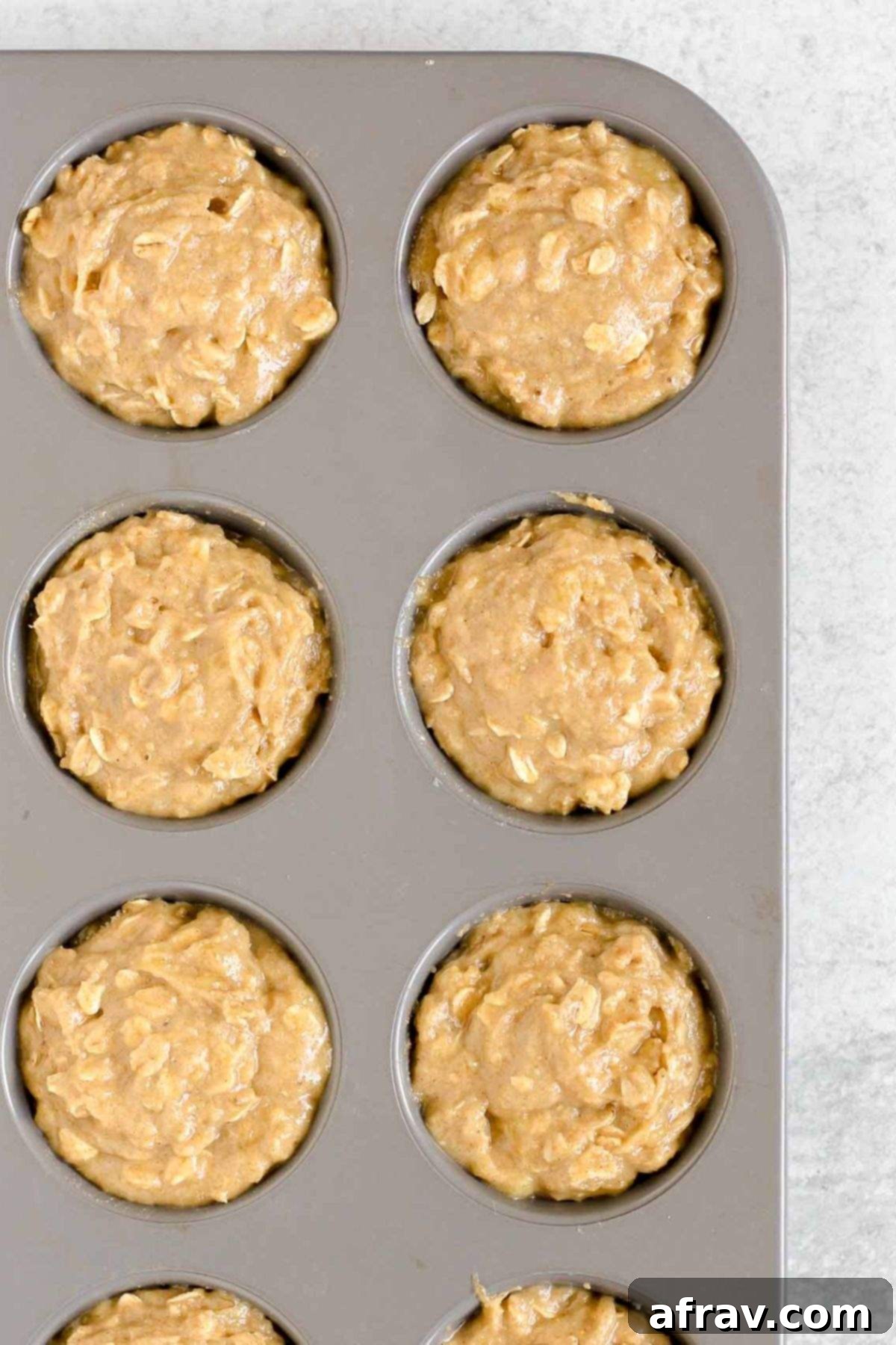 Banana muffin batter in a metal muffin pan.
