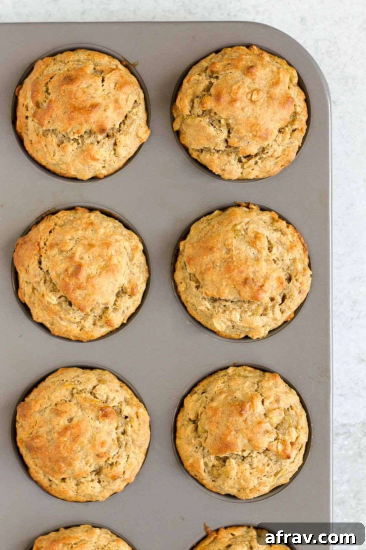 Gluten Free Banana Dream Muffins 9 Golden brown, freshly baked gluten-free banana muffins in a metal muffin pan, just out of the oven.